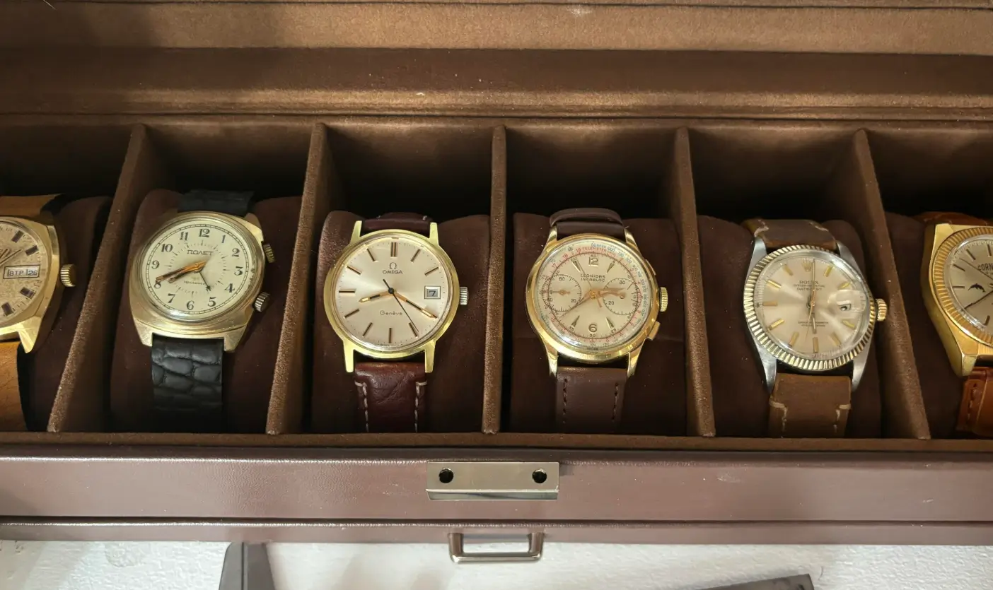 A collection of vintage watches neatly arranged in a brown watch box