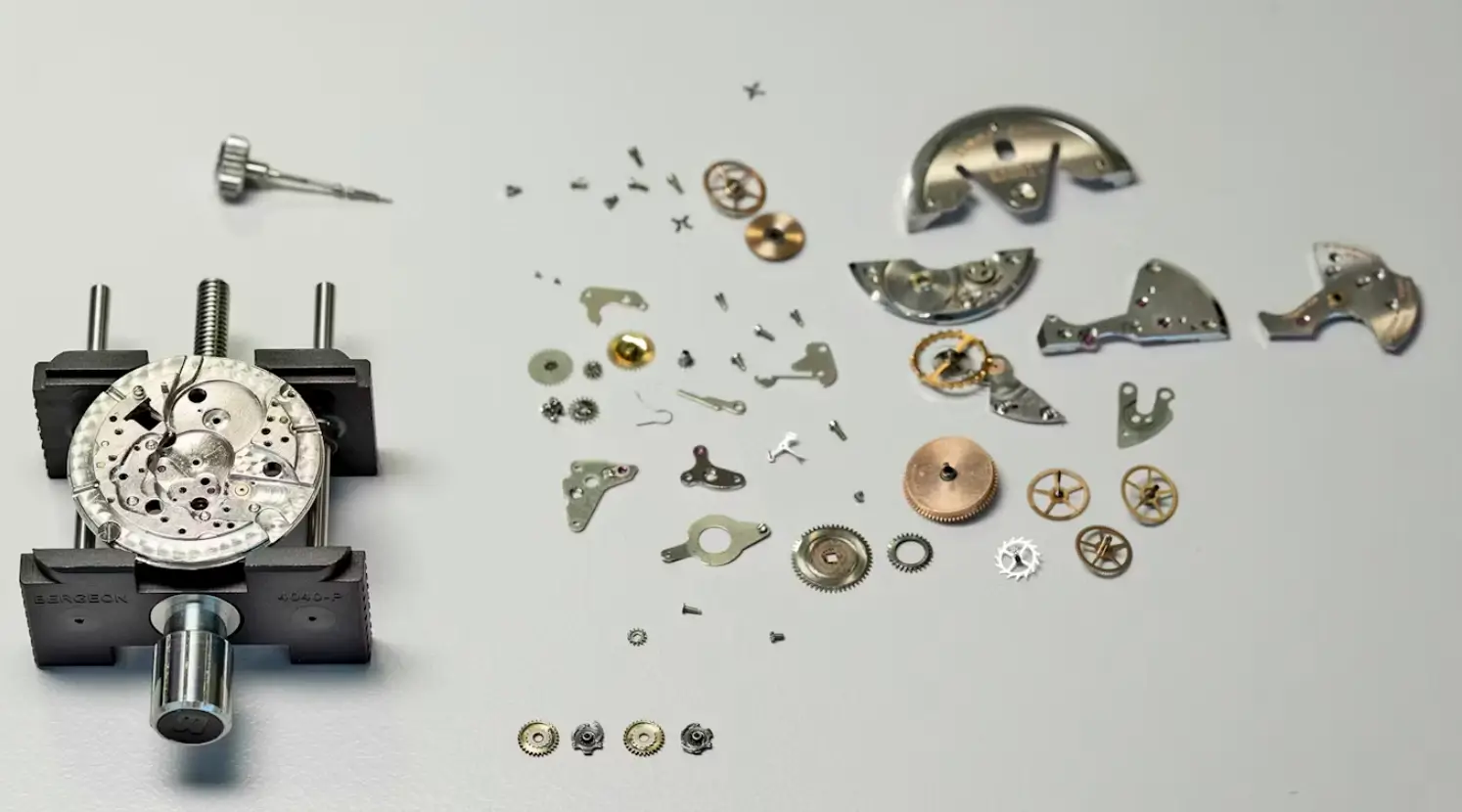 Vintage watch movement disassembled into various components, showcasing the intricate craftsmanship of classic timepieces.