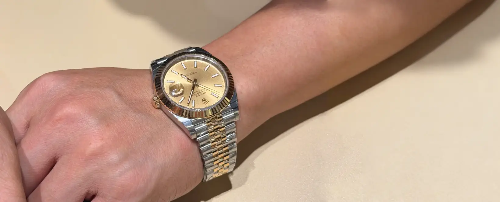 A hand wearing a Rolex 126333 A hand wearing a Rolex 126333, highlighting its two-tone bracelet and gold dial with diamond hour markers, capturing its daily elegance.